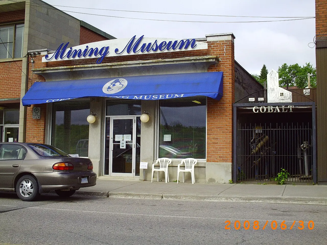 The brick storefront of the Cobalt Mining Museum on Silver Street, with a blue awning and a Cobalt sign on the gate beside it.
