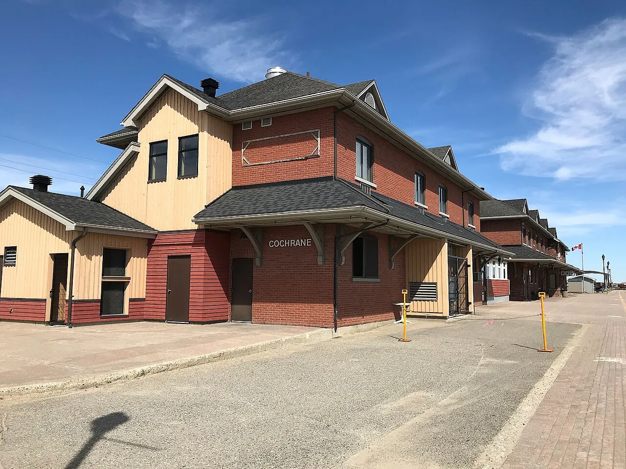 The red-brick and yellow-clad Cochrane railway station seen from the platform on a sunny day.