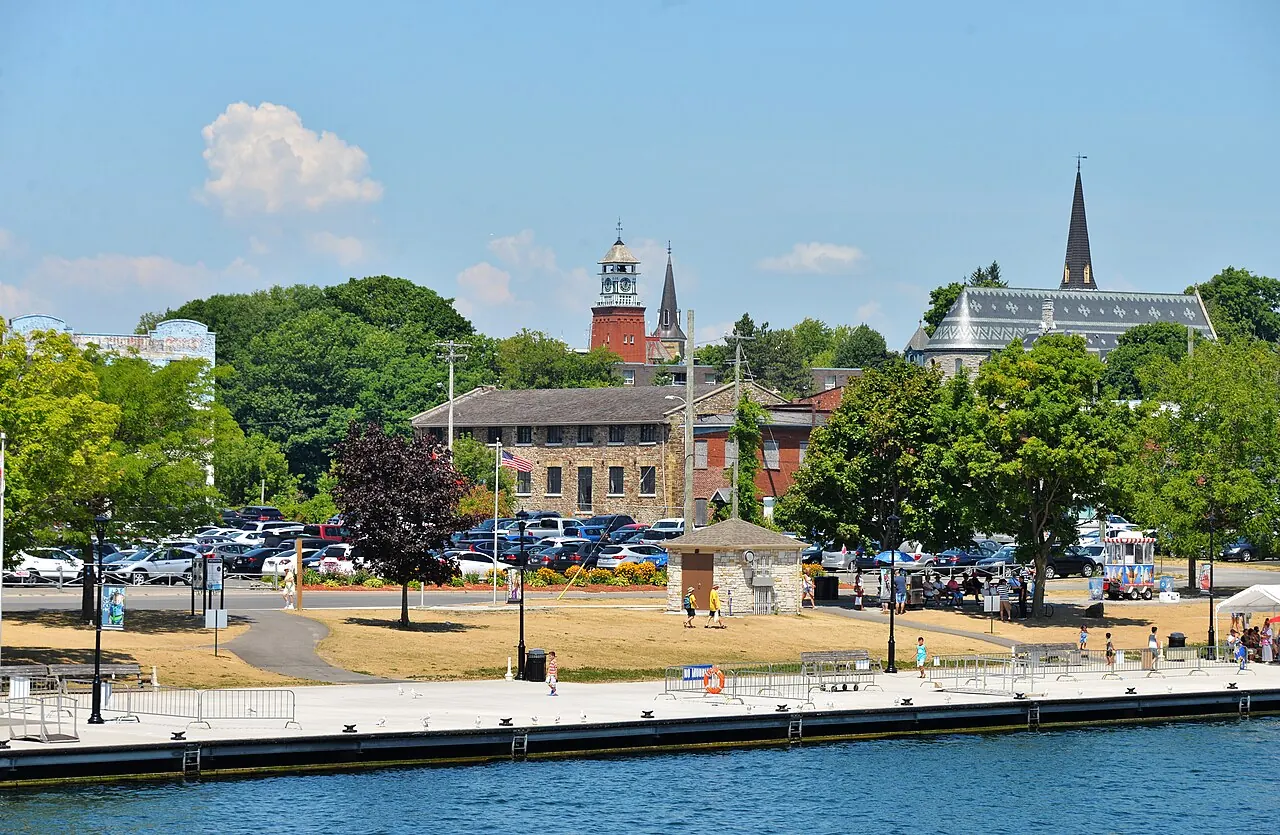 The Gananoque waterfront on a summer day, with the pier and park in front and church spires and old stone buildings behind.